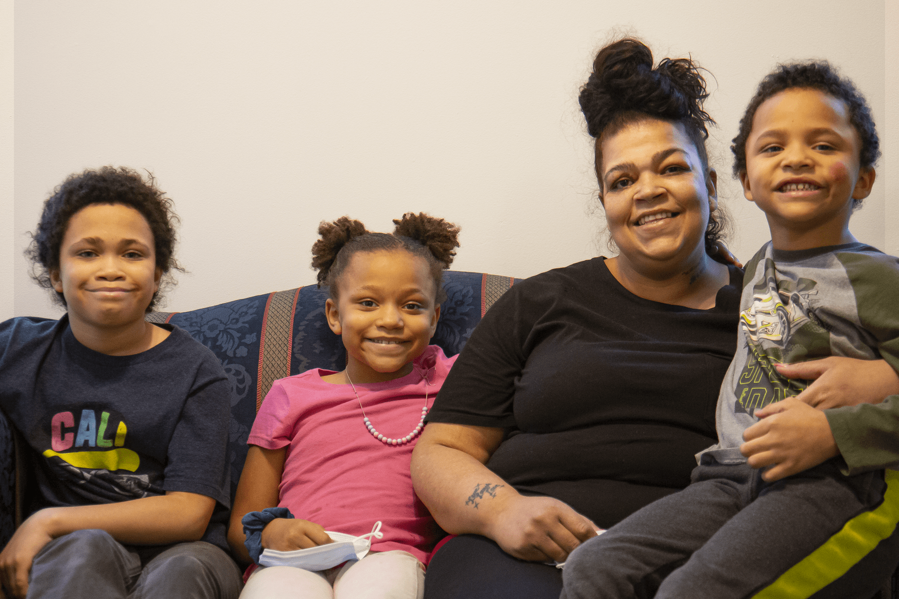 Family of 4 sitting on a couch smiling at the camera