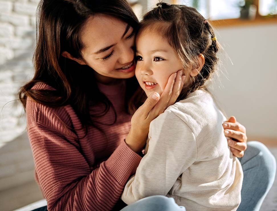 Working-Together-to-Create-Pathways-Forward Mother and daughter hugging each other in their bed room